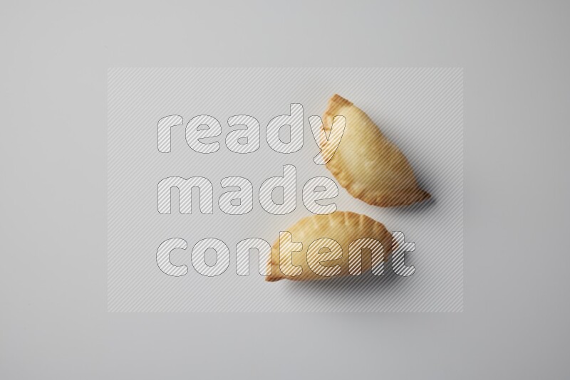 Two fried sambosa from a top angle on a white background