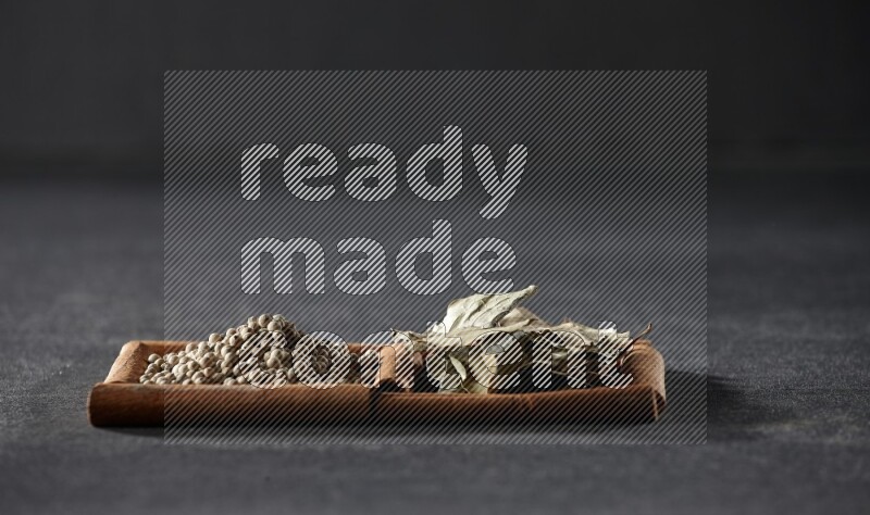 2 squares of cinnamon sticks full of white peppers and bay laurel leaves on black flooring