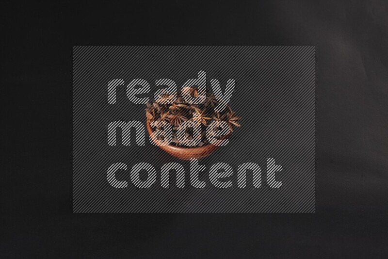 Star Anise in a wooden bowl on black flooring