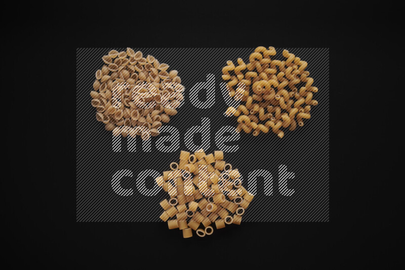 Different pasta types in bunches on black background
