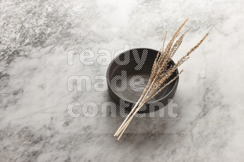 Wheat stalks on Black Pottery Oven Plate on grey marble flooring, 45 degree angel