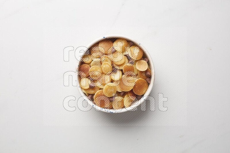 Top-view shot of chocolate chips cereal pancakes in a round bowl on white background