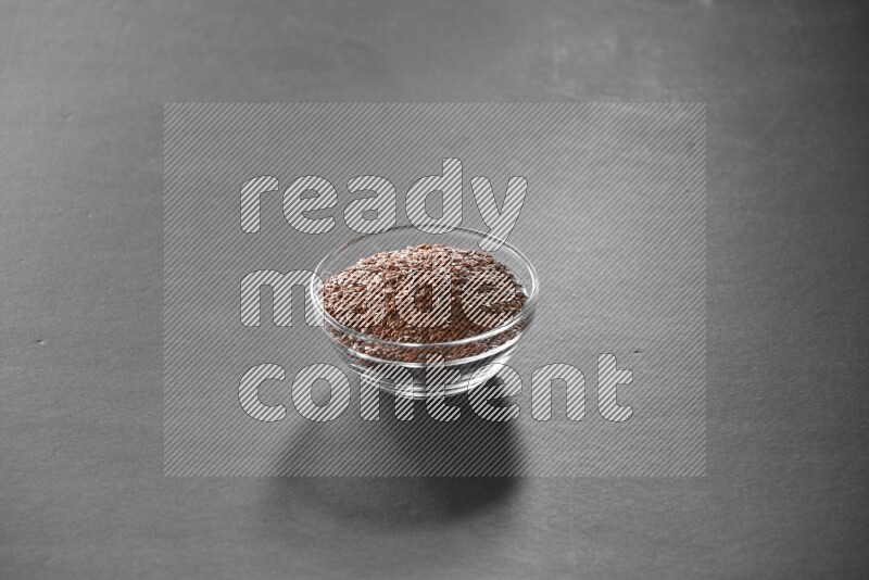 A glass bowl full of flax on black flooring