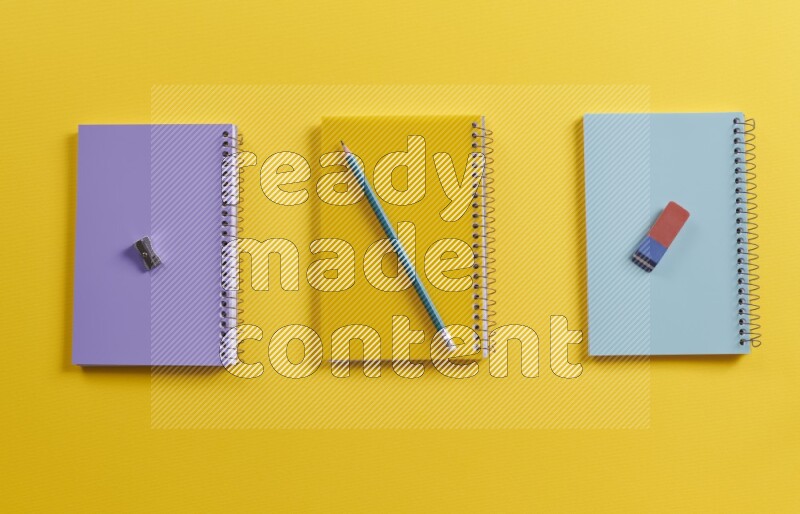 Multicolored notebooks with school supplies on yellow background