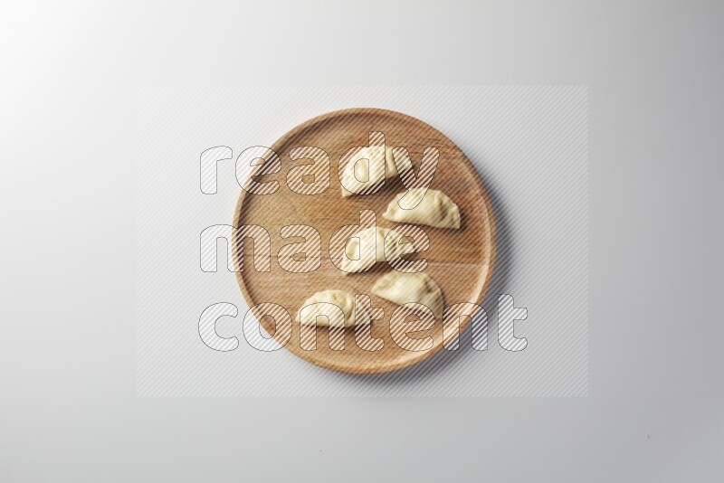 Five Sambosas on a wooden round plate on a white background