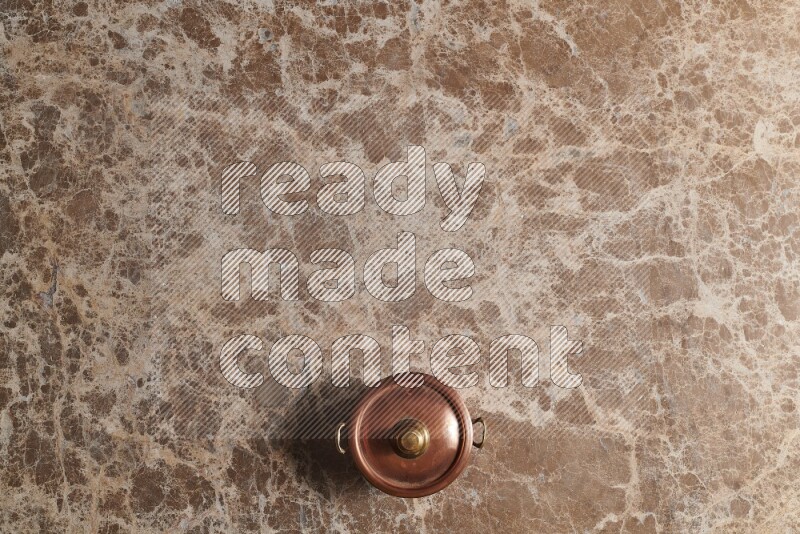 A small copper pot on beige marble background