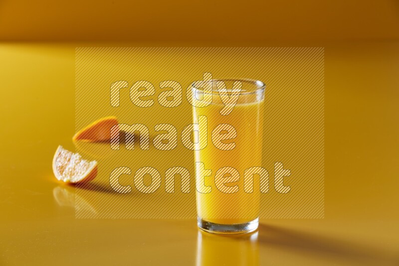 glass of orange juice on yellow background