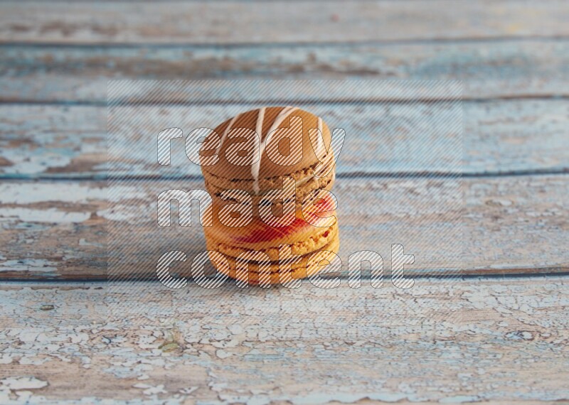 45º Shot of of two assorted Brown Irish Cream, and Orange Exotic macarons on light blue background