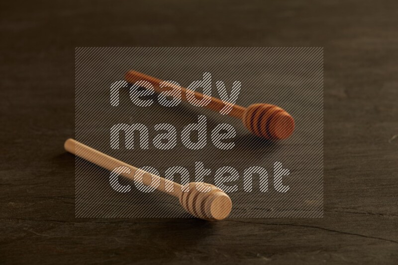 Wooden honey dipper on black slate background