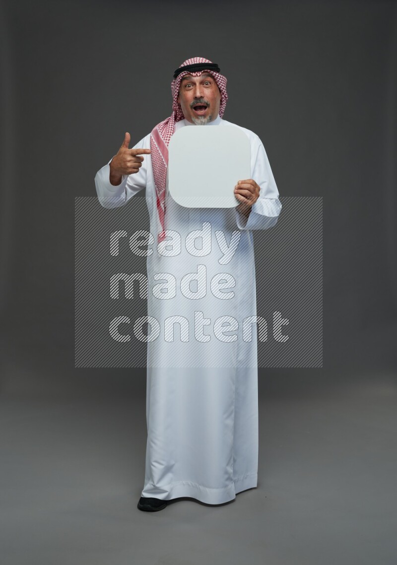 Saudi man with shomag Standing holding social media sing on gray background