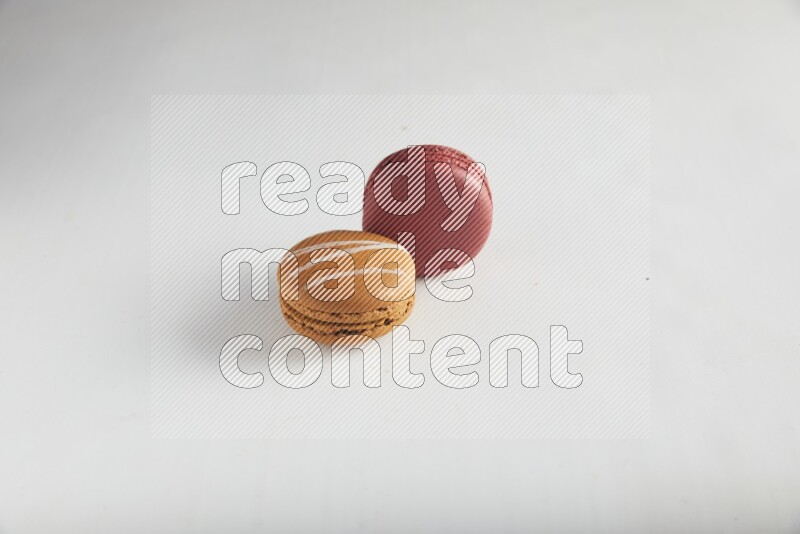 45º Shot of of two assorted Brown Irish Cream, and Red Velvet macarons on white background