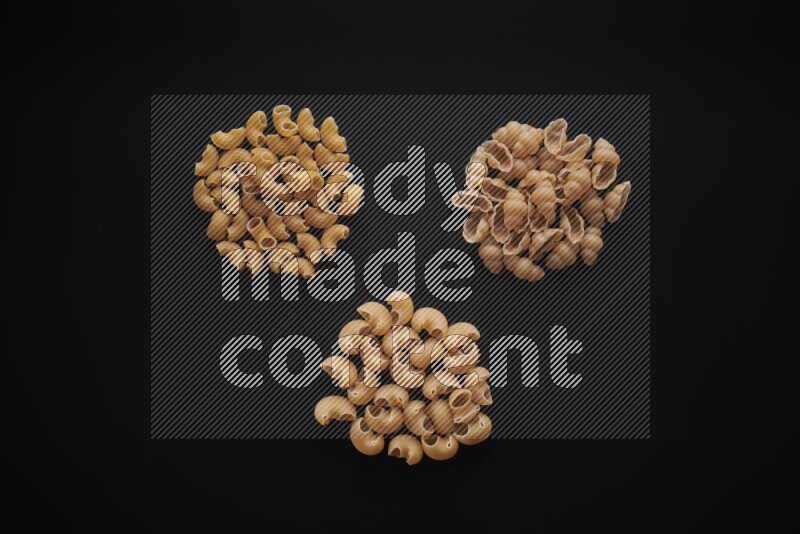 Different pasta types in bunches on black background