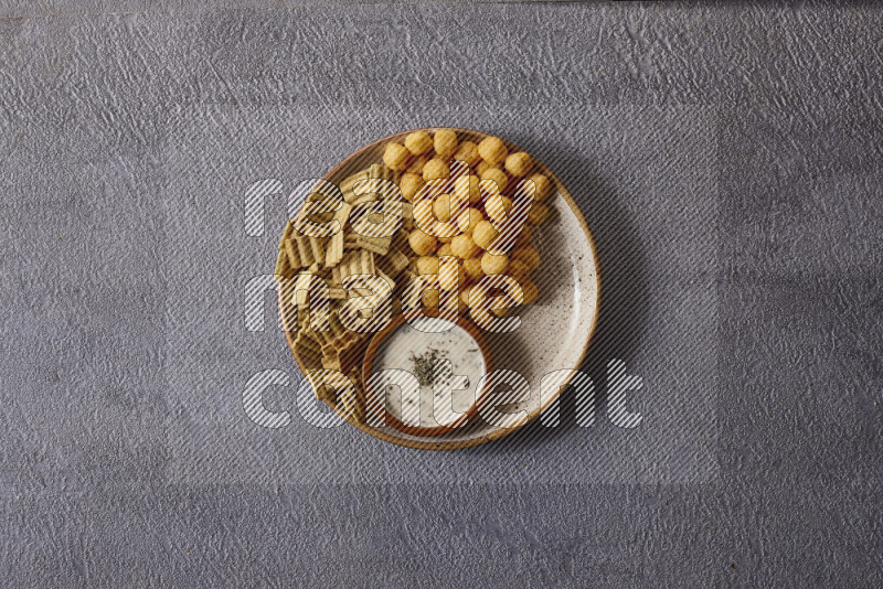 Assorted snacks in pottery bowls on grey background