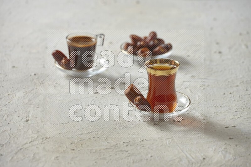 A tea glass cup with dates and coffee on textured white background