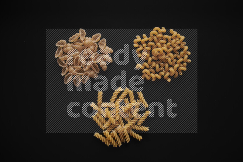 Different pasta types in bunches on black background