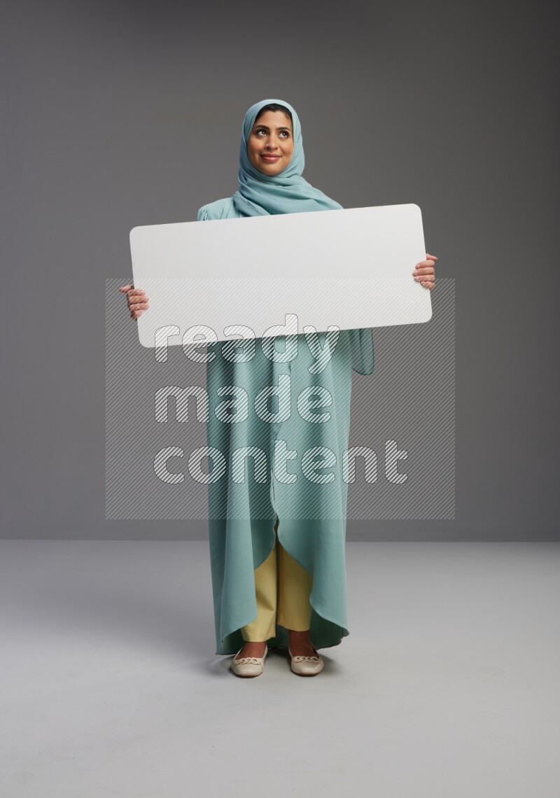 Saudi Woman wearing Abaya standing holding board on Gray background