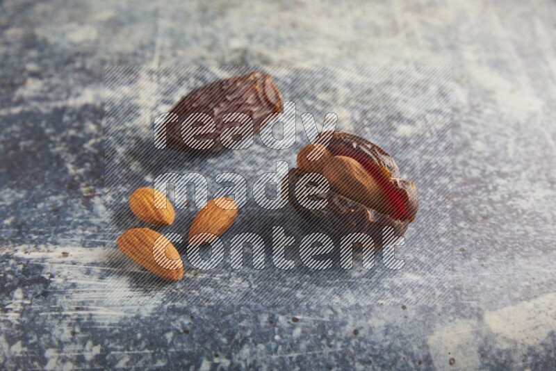 two almond stuffed madjoul dates on a rustic blue background