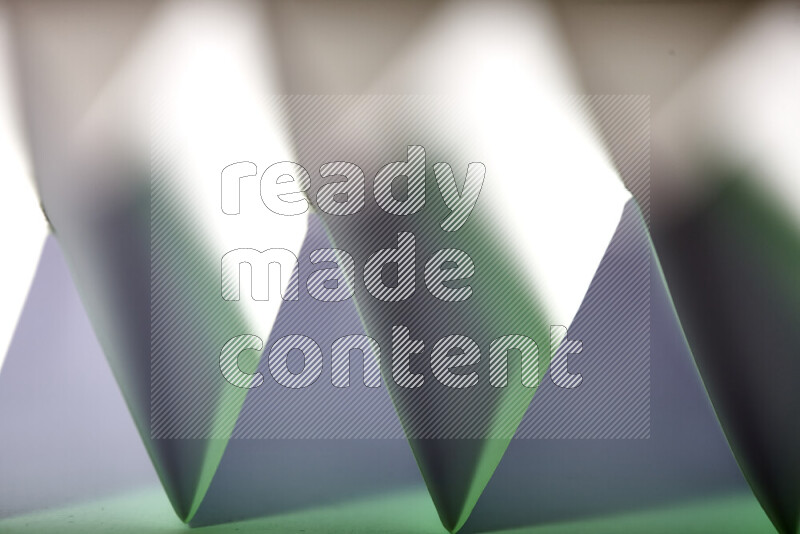 A close-up abstract image showing sharp geometric paper folds in white and green gradients