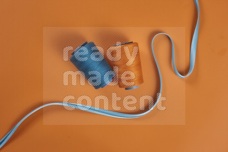 A blue collection of sewing and tailoring tools arranged on a orange background