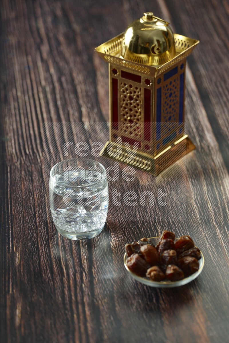 A golden lantern with different drinks, dates, nuts, prayer beads and quran on brown wooden background