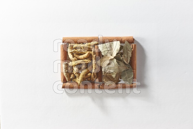 2 squares of cinnamon sticks full of turmeric fingers and bay laurel leaves on white flooring