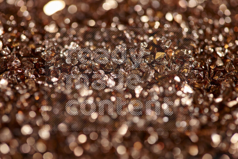 Bronze shimmering fragments of glass scattered on a black background