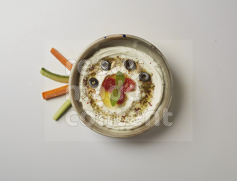 Lebnah garnished with cherry tomato, mint, olives & pine nuts in a grey pottery plate on a white background