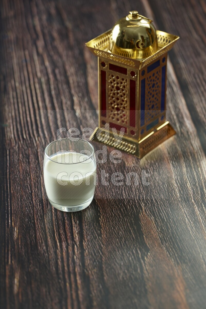 A golden lantern with different drinks, dates, nuts, prayer beads and quran on brown wooden background