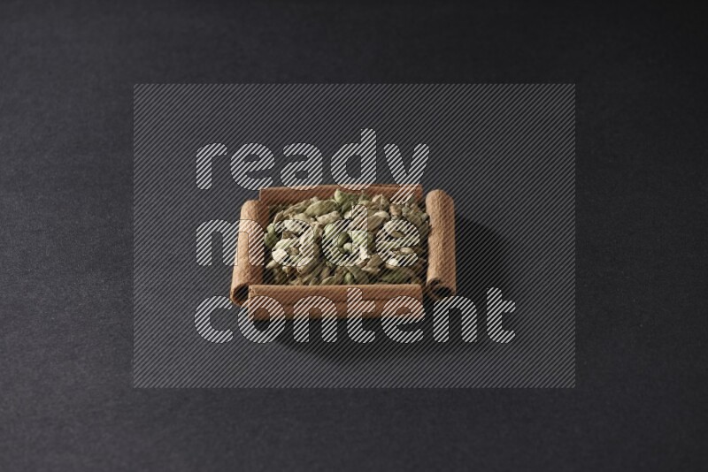A single square of cinnamon sticks full of Cardamom on black flooring