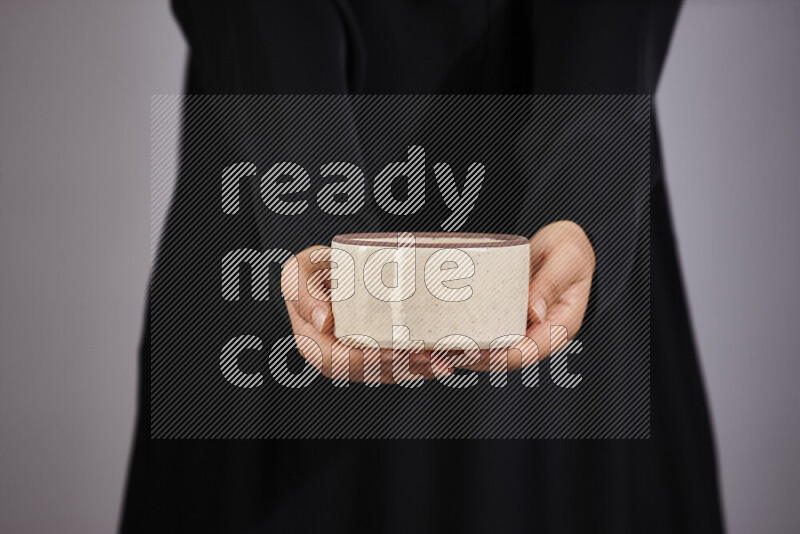 A woman in black abaya holding different pottery essentials in different positions