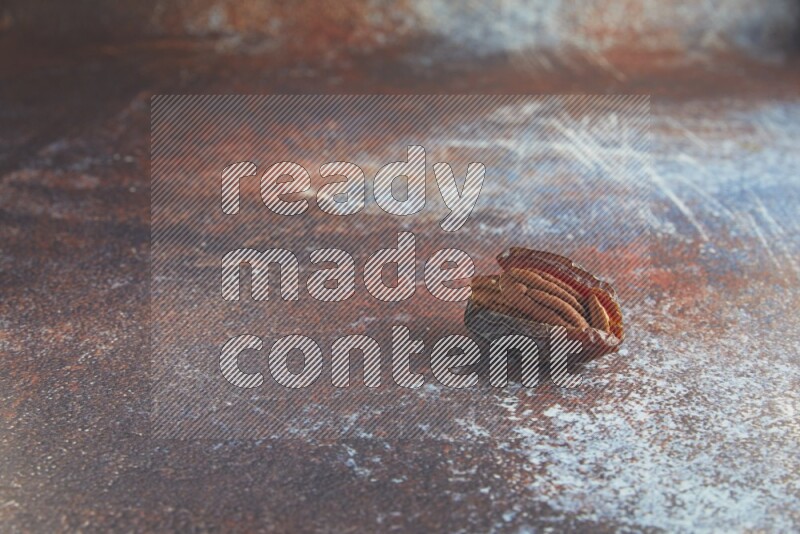 one pecan stuffed madjoul date on a rustic reddish background