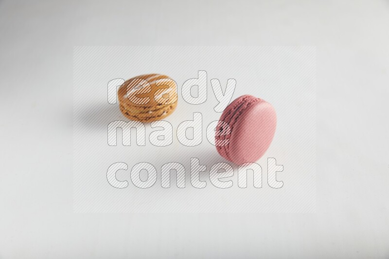 45º Shot of of two assorted Brown Irish Cream, and Pink Raspberry macarons on white background