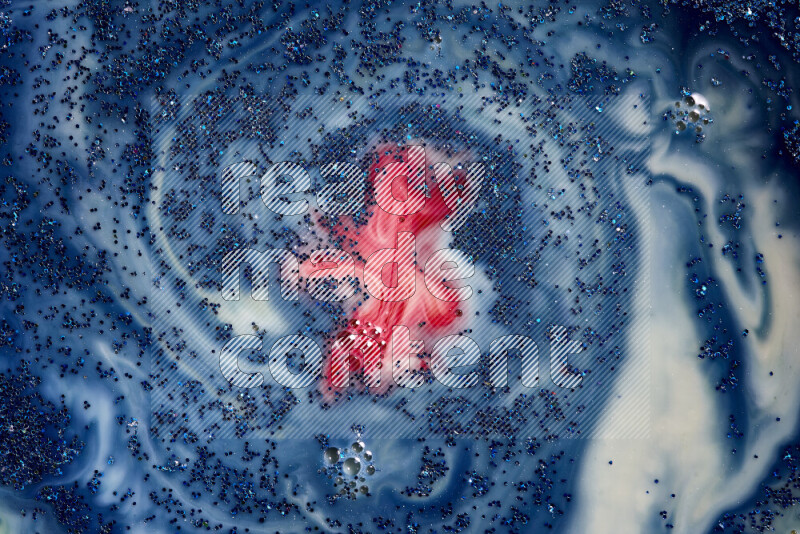 A close-up of sparkling blue glitter scattered on swirling blue and red background