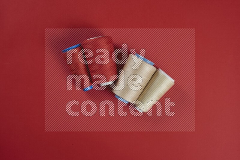 مجموعة من أدوات الخياطة والتفصيل بنية وحمراء اللون على خلفية حمراء