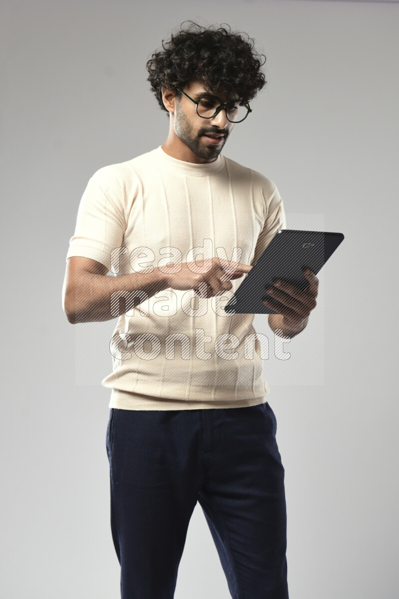 A man wearing casual standing and browsing on a tablet on white background