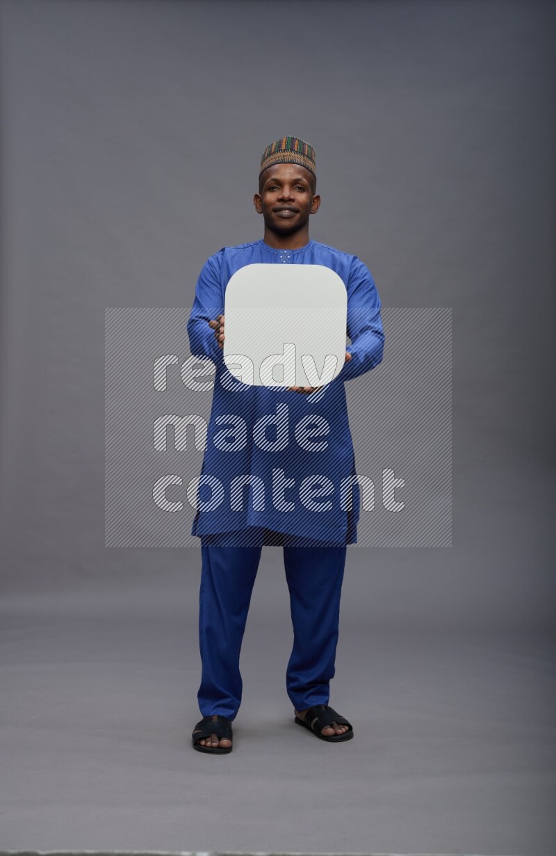 Man wearing Nigerian outfit standing holding social media sign on gray background