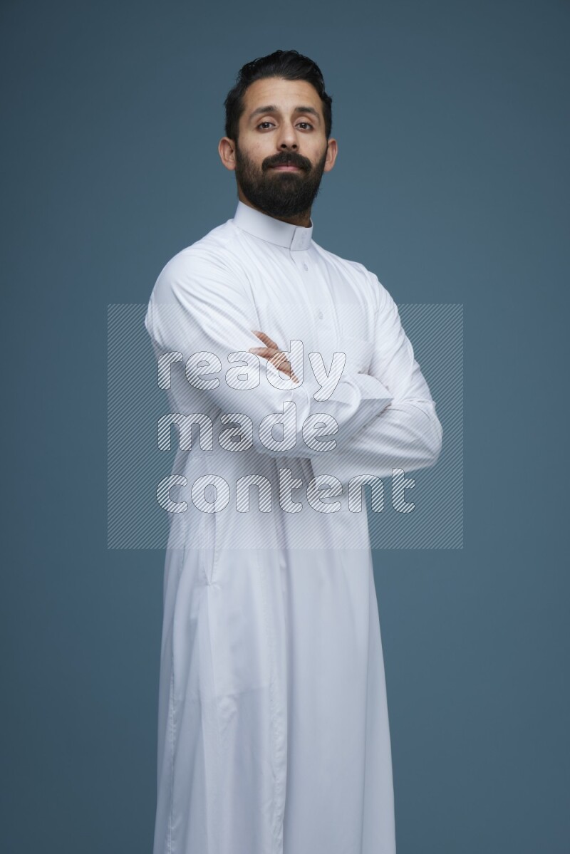 A man posing in a blue background wearing Saudi Thob