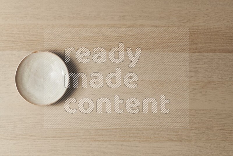 A beige pottery plate on light wooden background