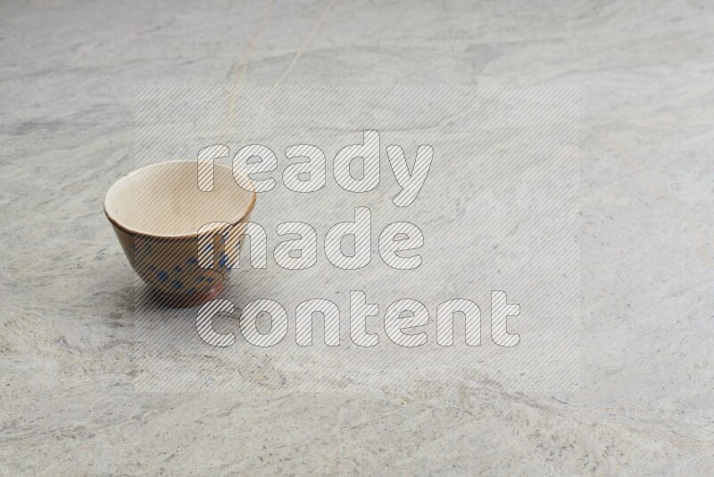 A multicolored pottery bowl on grey marble background