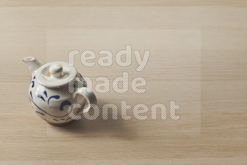 إبريق شاي فخاري على خلفية خشبية فاتحة