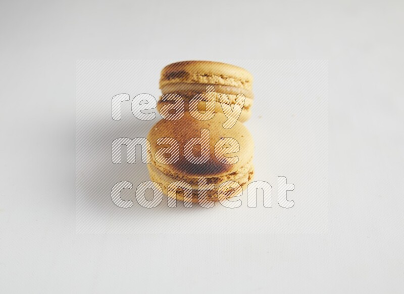 45º Shot of two Yellow Crème Brulée macarons on white background