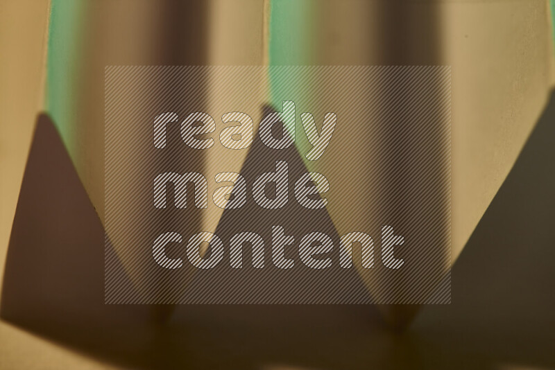 صورة مجردة مقربة تظهر طيات ورقية هندسية حادة بتدرجات اللون الأخضر مع درجات لونية دافئة