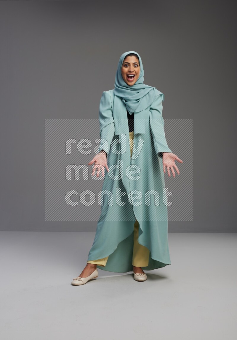 Saudi Woman wearing Abaya standing interacting with the camera on Gray background