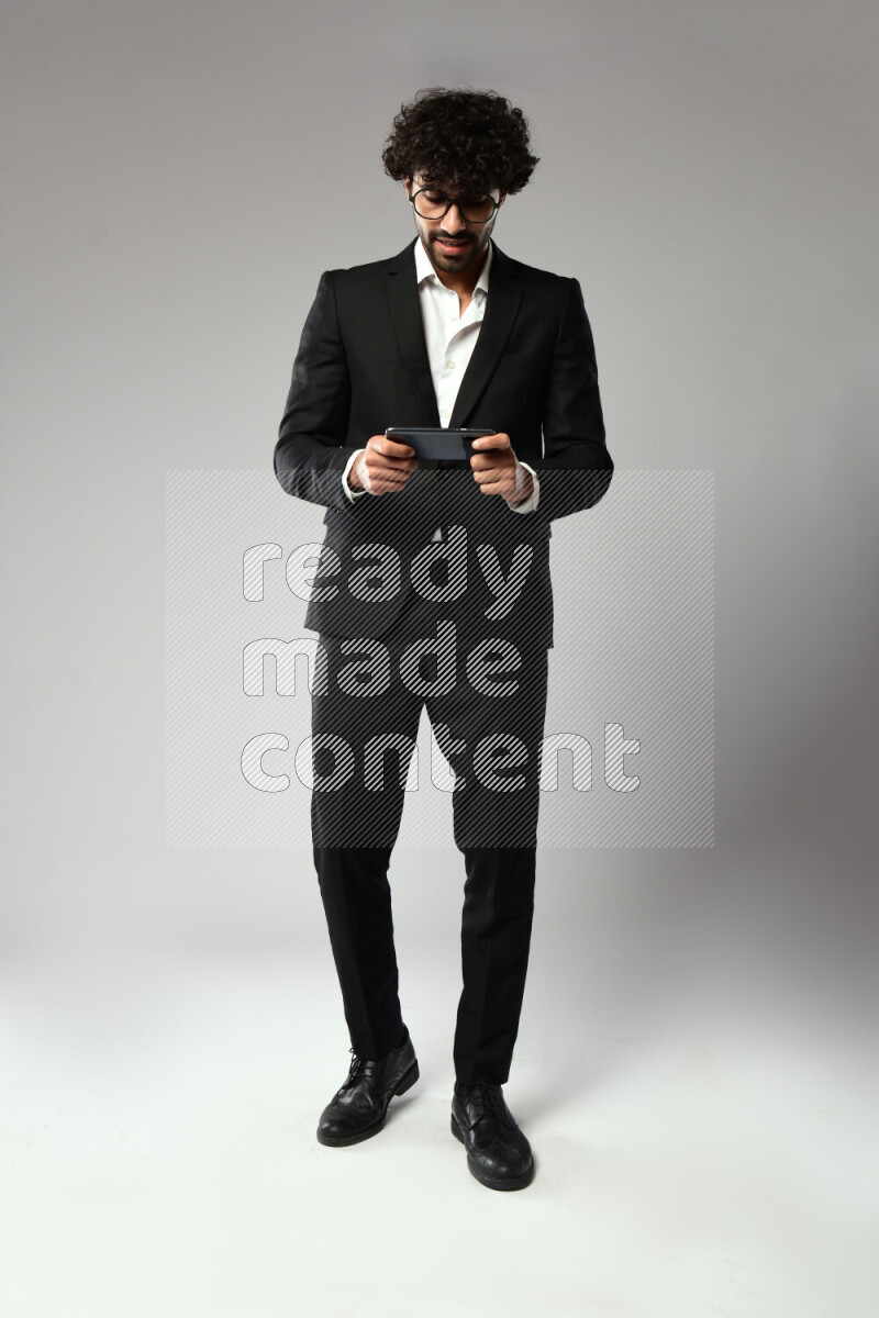 A man wearing formal standing and gaming on the phone on white background