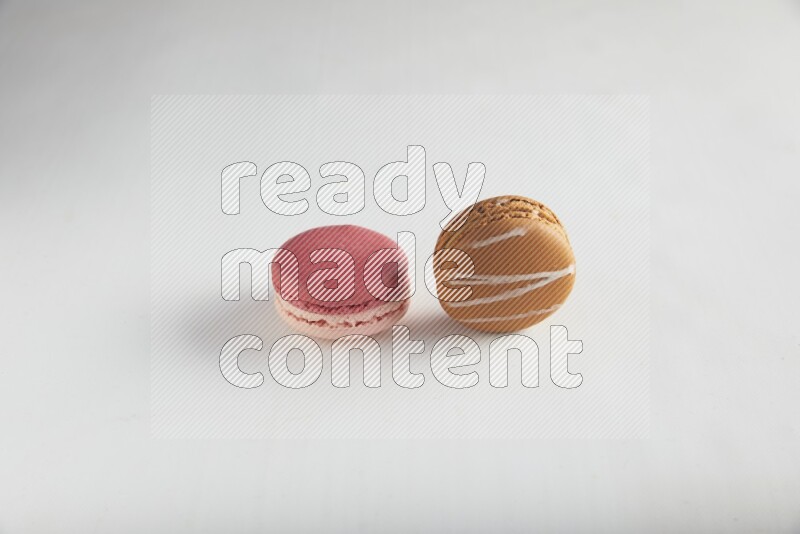 45º Shot of of two assorted Brown Irish Cream, and Pink Litchi Raspberry macarons on white background