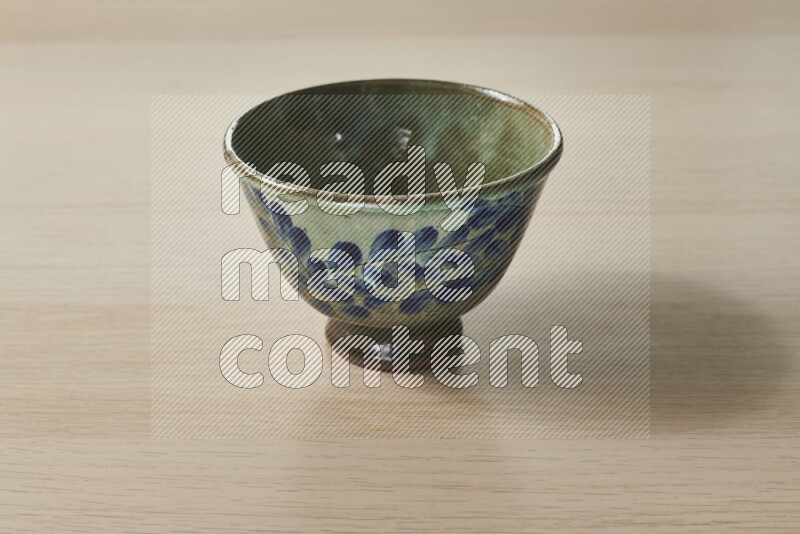 A decorative pottery bowl on light wooden background