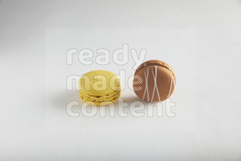 45º Shot of of two assorted Brown Irish Cream, and Yellow Lemon macarons on white background