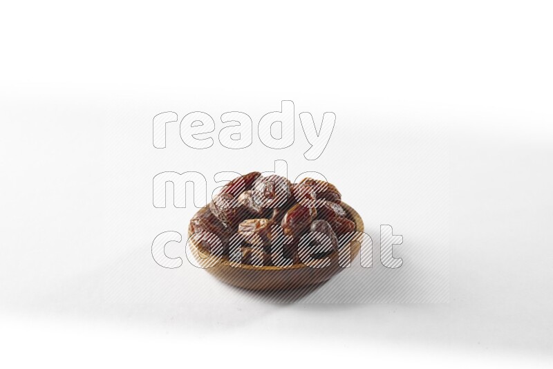 Dates in a wooden bowl on white background