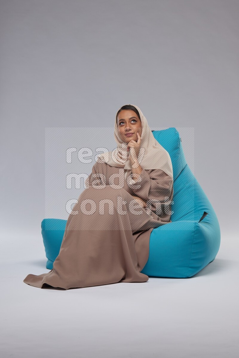 A woman sitting on a blue beanbag and interacting with the camera