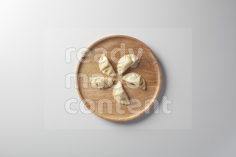 Five Sambosas on a wooden round plate on a white background